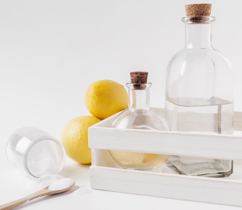 Glass bottles with cork tops next to lemons and a white power on a spoon