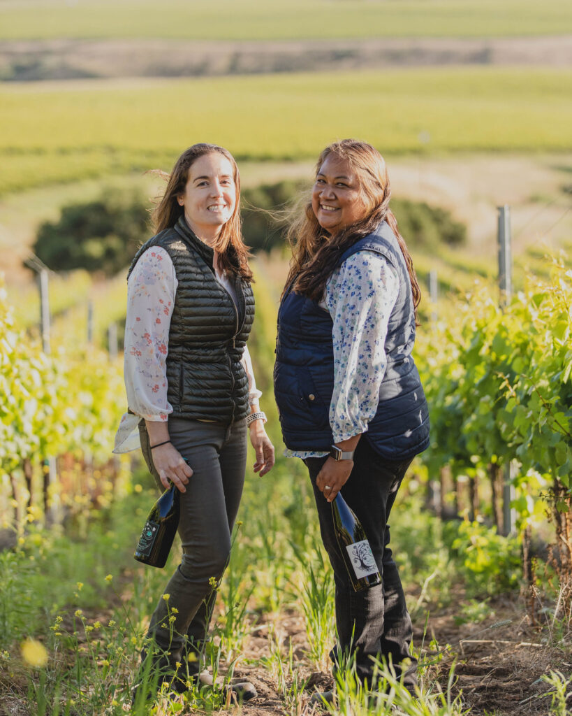 Tara Gomez and Mireia Taribó holding bottles of Camins 2 Dreams while standing in a vineyard